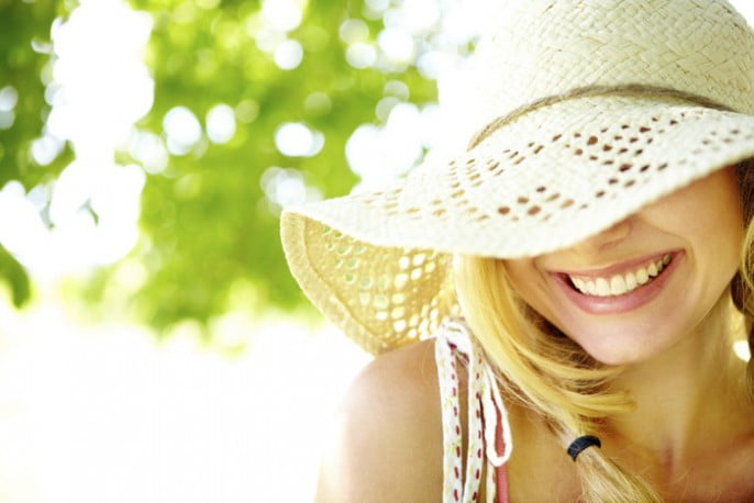 Smiling blonde with hat covering eyes with copyspace