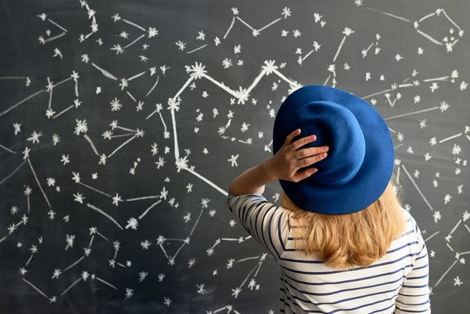woman looking at chalkboard drawing of zodiac signs