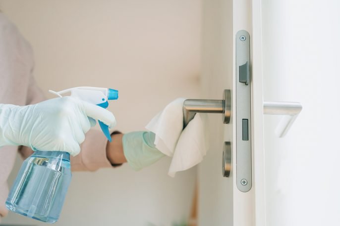 Gloved hand sanitizing doorknob.