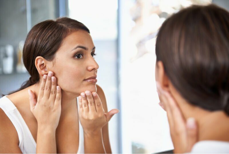 Woman Peers Closely at Skin in Mirror After Injectable Fillers and BOTOX 